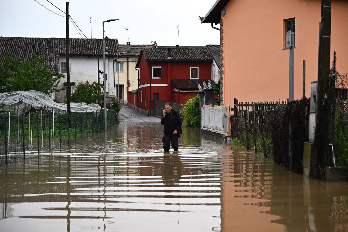 A resident speaks on his phone while walking a flooded street in the village of Carde, Cuneo, near Turin in northwestern Italy on Sunday.