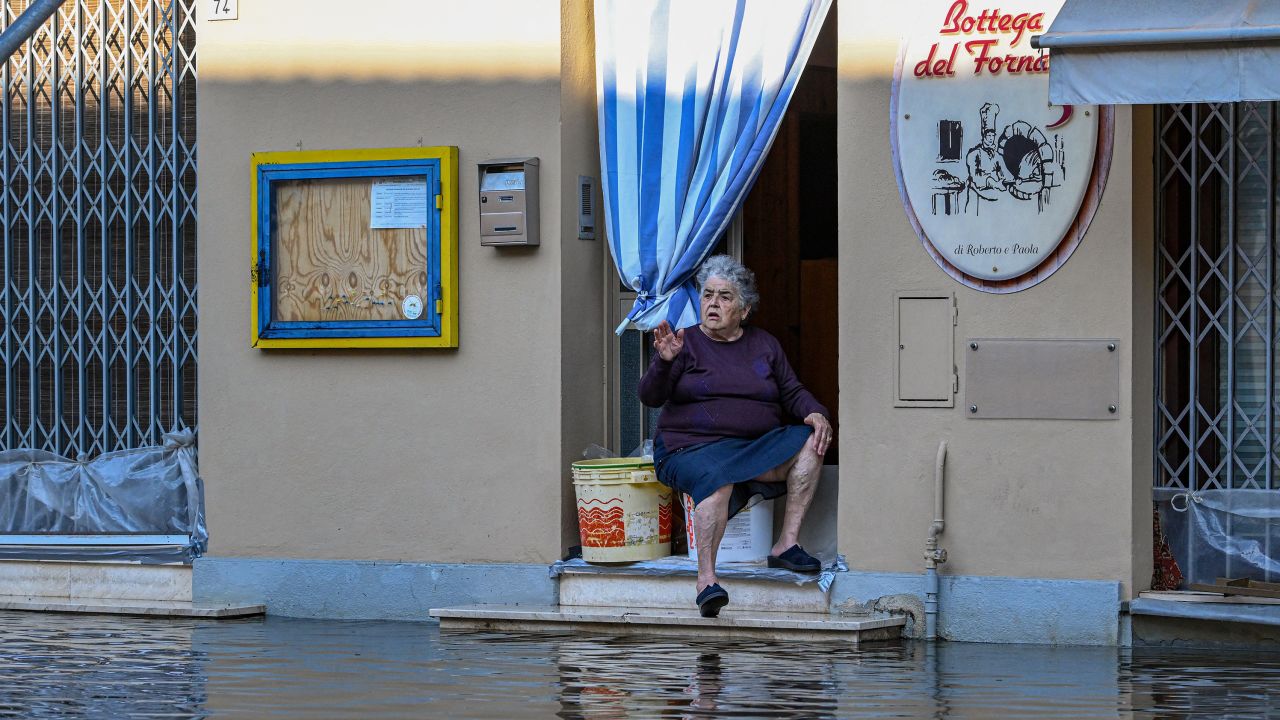 A resident sits on the doorstep of a bakery in a flooded street on May 21, 2023 in Conselice, near Ravenna.