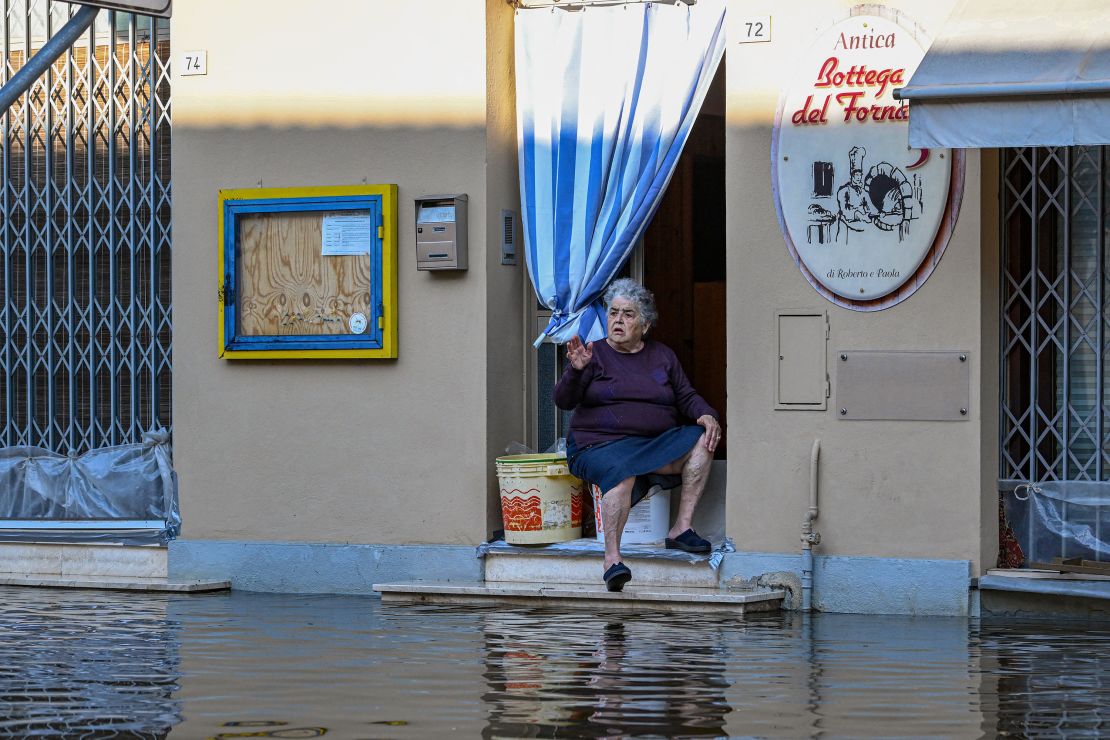 A resident sits on the doorstep of a bakery in a flooded street on May 21, 2023 in Conselice, near Ravenna.