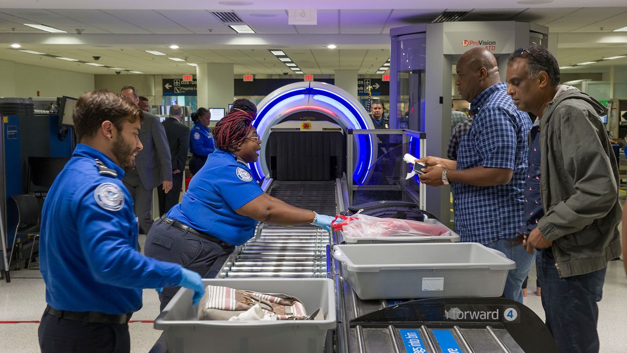 MIAMI, FLORIDA - MAY 21: Transportation Security Administration (TSA) agents help travelers place their bags through the 3-D scanner at the Miami International Airport on May 21, 2019 in Miami, Florida. TSA has begun using the new 3-D computed tomography (CT) scanner in a checkpoint lane to detect explosives and other prohibited items that may be inside carry-on bags.  (Photo by Joe Raedle/Getty Images)