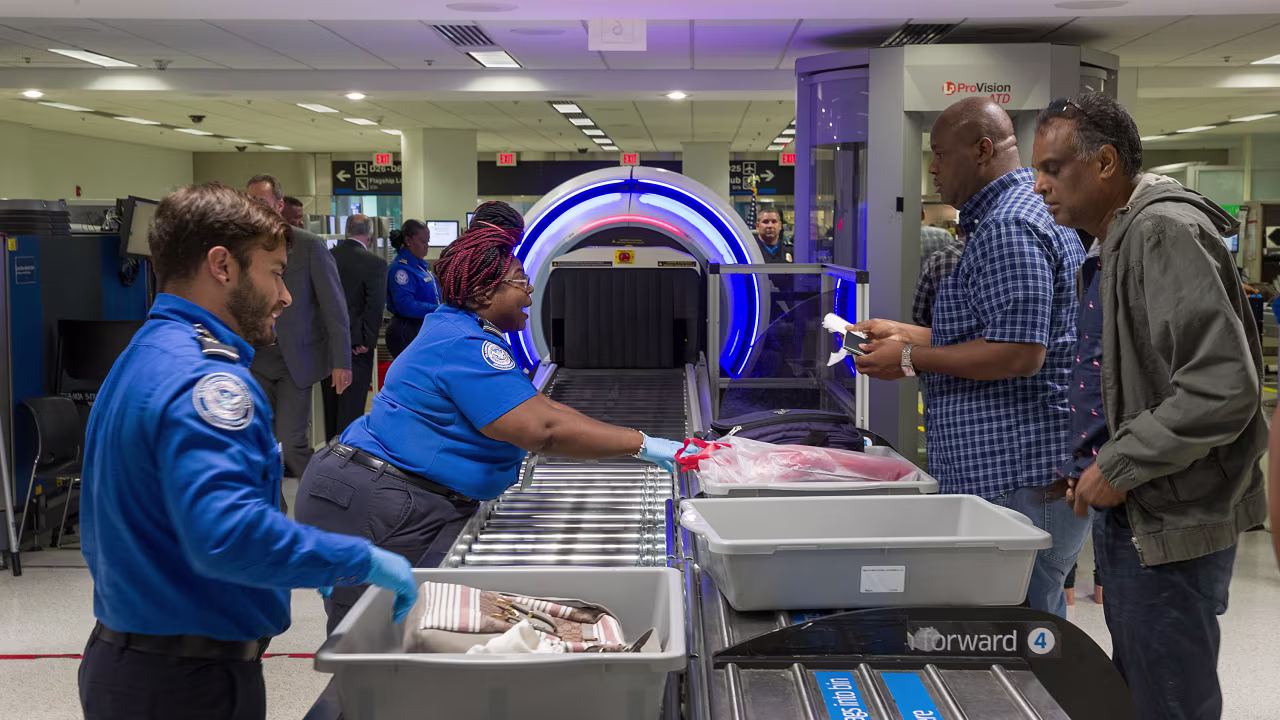 MIAMI, FLORIDA - MAY 21: Transportation Security Administration (TSA) agents help travelers place their bags through the 3-D scanner at the Miami International Airport on May 21, 2019 in Miami, Florida. TSA has begun using the new 3-D computed tomography (CT) scanner in a checkpoint lane to detect explosives and other prohibited items that may be inside carry-on bags.  (Photo by Joe Raedle/Getty Images)