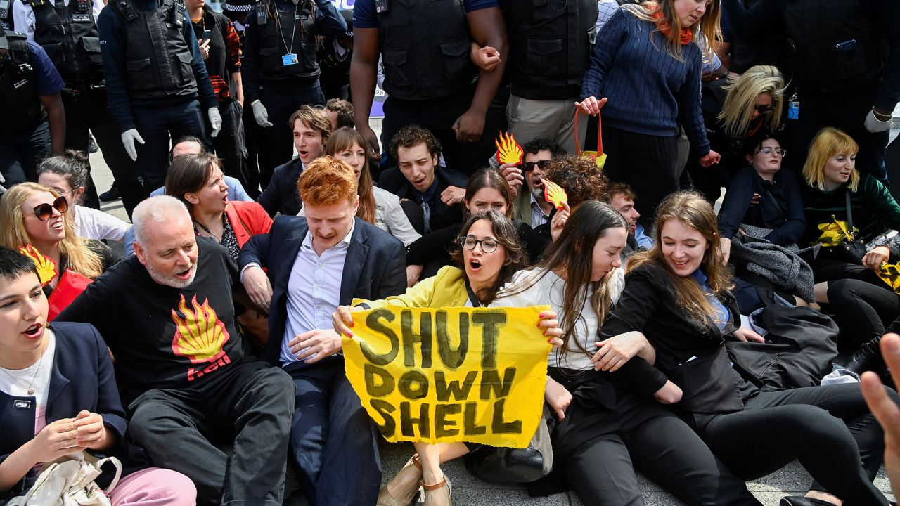 Protesters sit in front of security personnel during the Fossil Free London demonstration outside the venue of Shell's annual shareholder meeting.