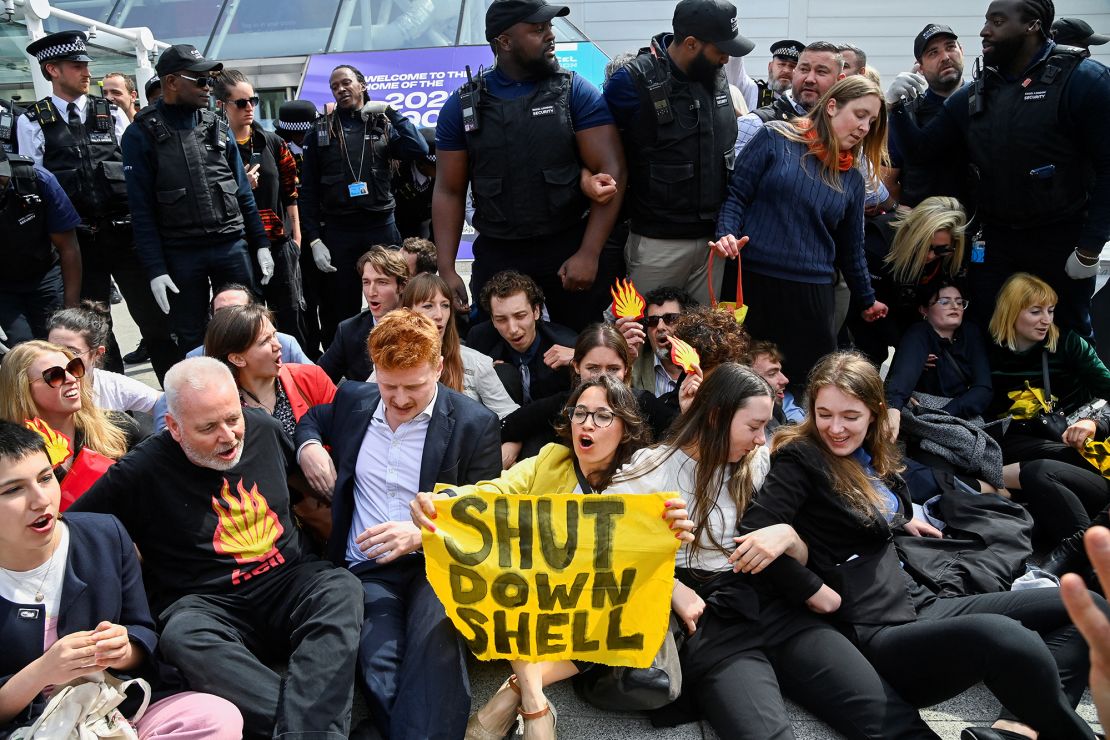 Protesters sit in front of security personnel during the Fossil Free London demonstration outside the venue of Shell's annual shareholder meeting.