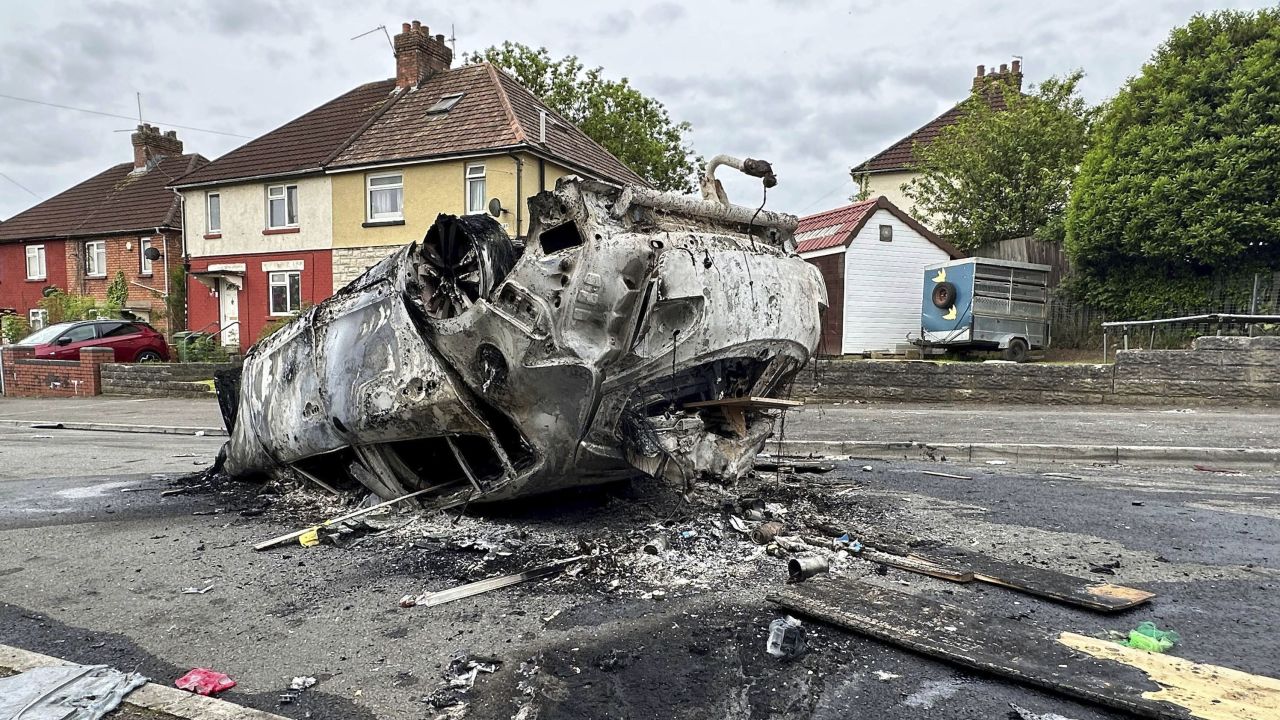 A burnt vehicle lies on the street, in the aftermath of the riots.