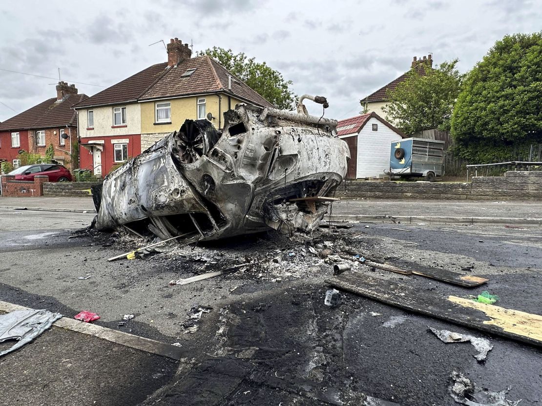 A burnt vehicle lies on the street, in the aftermath of the riots.