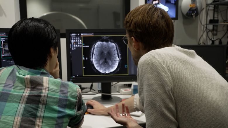 Assistant Professor Alexander Huth (right) and PhD Student Jerry Tang review brain imaging from CNN Correspondent Donie O'Sullivan.