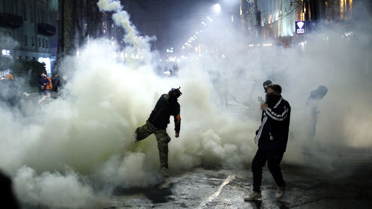 Demonstrators throw tear gas back at police during the