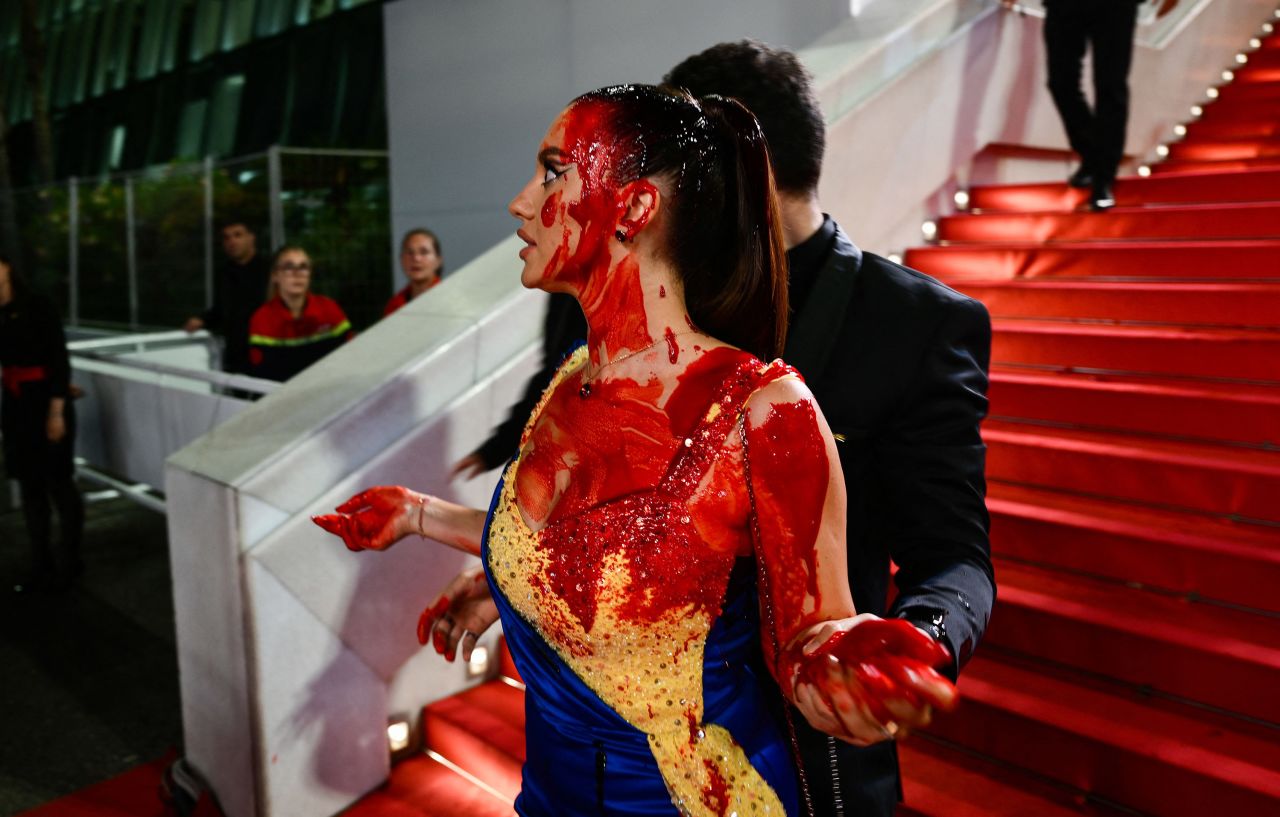 A protester, wearing a dress in the colours of the Ukrainian flag, is detained by security after she covered herself in fake blood on the stairs on the Festival Palace ahead of the screening of the film "Acide" during the 76th edition of the Cannes Film Festival in Cannes, southern France, on May 21, 2023. (Photo by CHRISTOPHE SIMON / AFP) (Photo by CHRISTOPHE SIMON/AFP via Getty Images)
