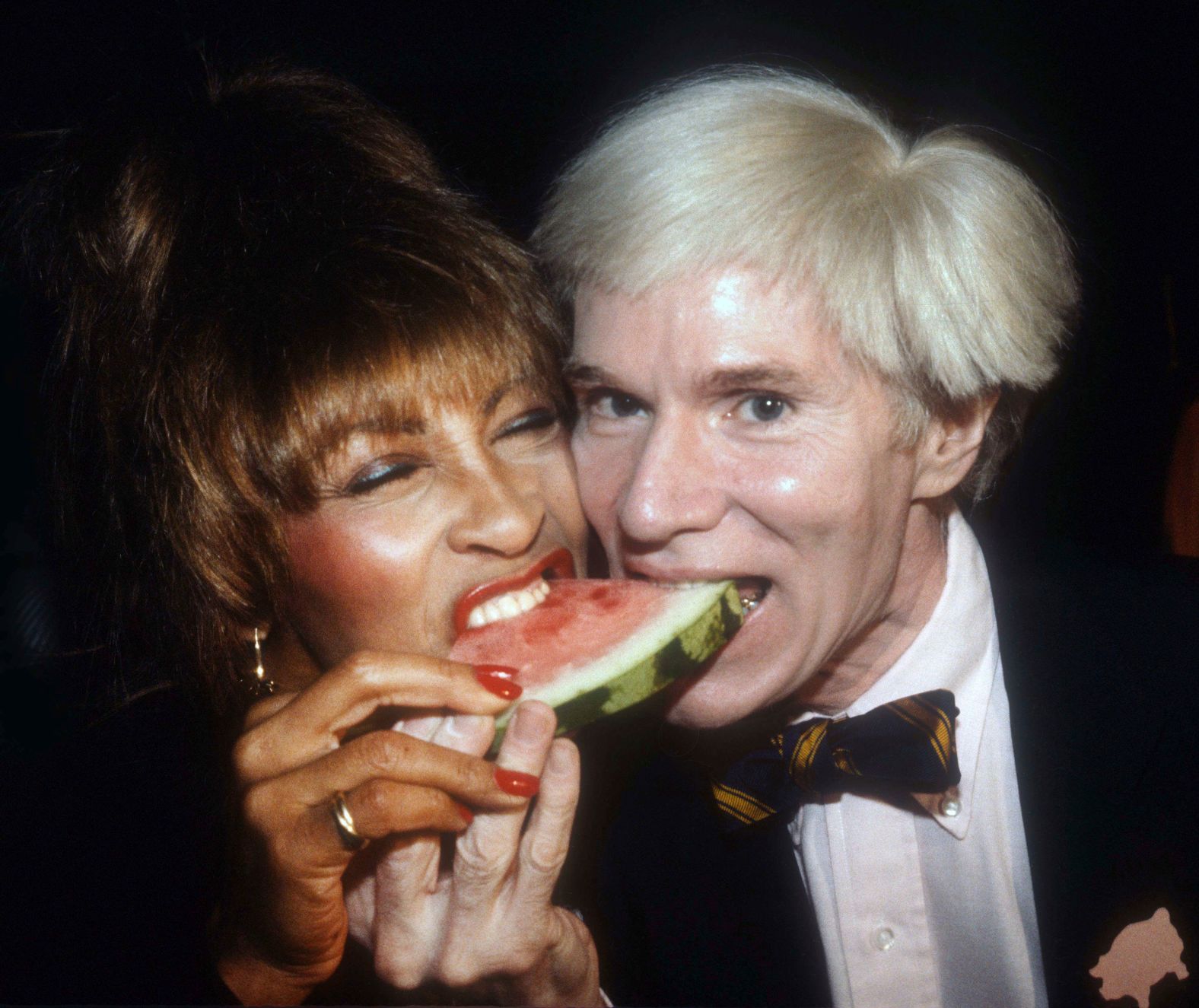 Turner and artist Andy Warhol share watermelon in 1981.