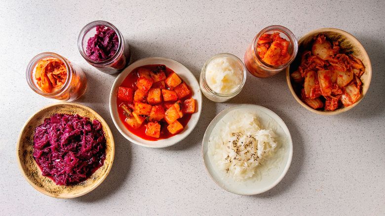 Variety of fermented food korean traditional kimchi cabbage and radish salad, white and red sauerkraut in glass jars and ceramic plates over grey spotted background, Flat lay, space. (Photo by: Natasha Breen/REDA&CO/Universal Images Group via Getty Images)