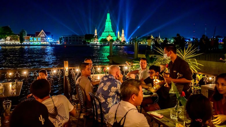 People dine on a restaurant terrace in front of the stupa of the Buddhist temple Wat Arun (Temple of Dawn) illuminated in green to mark St. Patrick's Day in Bangkok on March 17, 2021. (Photo by Mladen ANTONOV / AFP) (Photo by MLADEN ANTONOV/AFP via Getty Images)