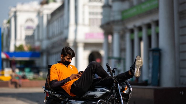 An online food deliveryman checks his mobile phone resting on a motorbike as he waits for orders during a government-imposed nationwide lockdown as a preventive measure against the spread of the COVID-19 coronavirus in New Delhi on April 27, 2020. (Photo by Jewel SAMAD / AFP) (Photo by JEWEL SAMAD/AFP via Getty Images)