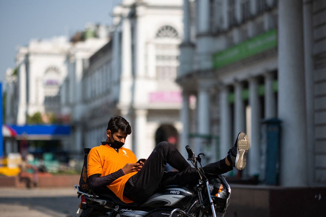 An online food deliveryman checks his mobile phone resting on a motorbike as he waits for orders during a government-imposed nationwide lockdown as a preventive measure against the spread of the COVID-19 coronavirus in New Delhi on April 27, 2020. (Photo by Jewel SAMAD / AFP) (Photo by JEWEL SAMAD/AFP via Getty Images)