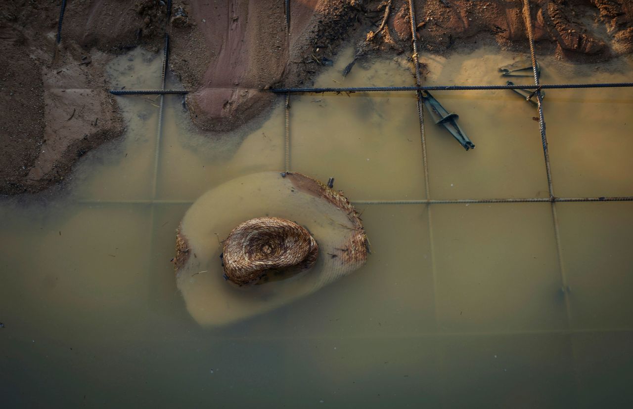A straw hat sits in a puddle where a house under construction collapsed during high winds in Conroe, Texas, on Tuesday, May 23. Officials reported fatalities and injuries.