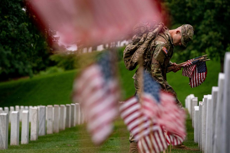 A member of the US Army's 3rd US Infantry Regiment, also known as The Old Guard, places flags in front of each headstone at Arlington National Cemetery on Thursday, May 25. The "Flags In" tradition takes place every year before Memorial Day.