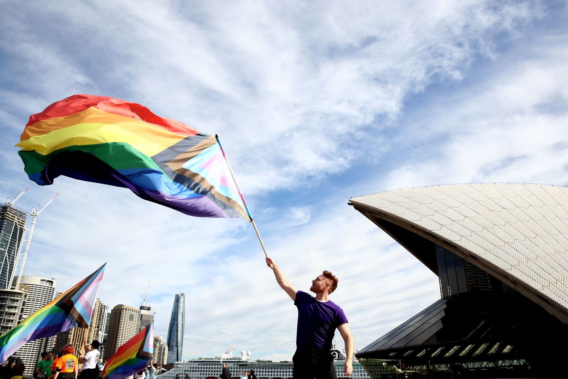 SYDNEY, AUSTRALIA - JUNE 24: A man wields a rainbow flag as 1,000 people form a human progress flag on the steps of the Opera House to mark the 44th anniversary or the Sydney Gay and Lesbian Mardis Gras Sydney Opera House on June 24, 2022 in Sydney, Australia. Australia will host WorldPride 2023.