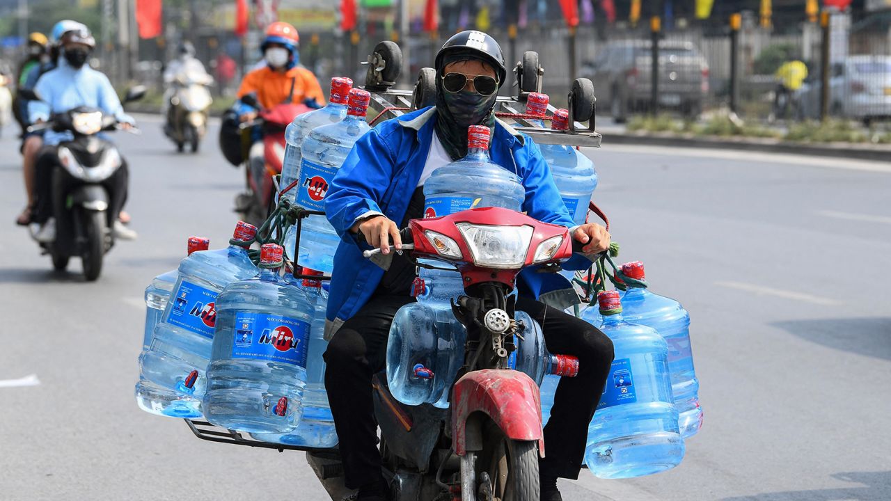 This photo taken on May 22, 2023, shows a man transporting containers of water on his motorbike in Hanoi, Vietnam.