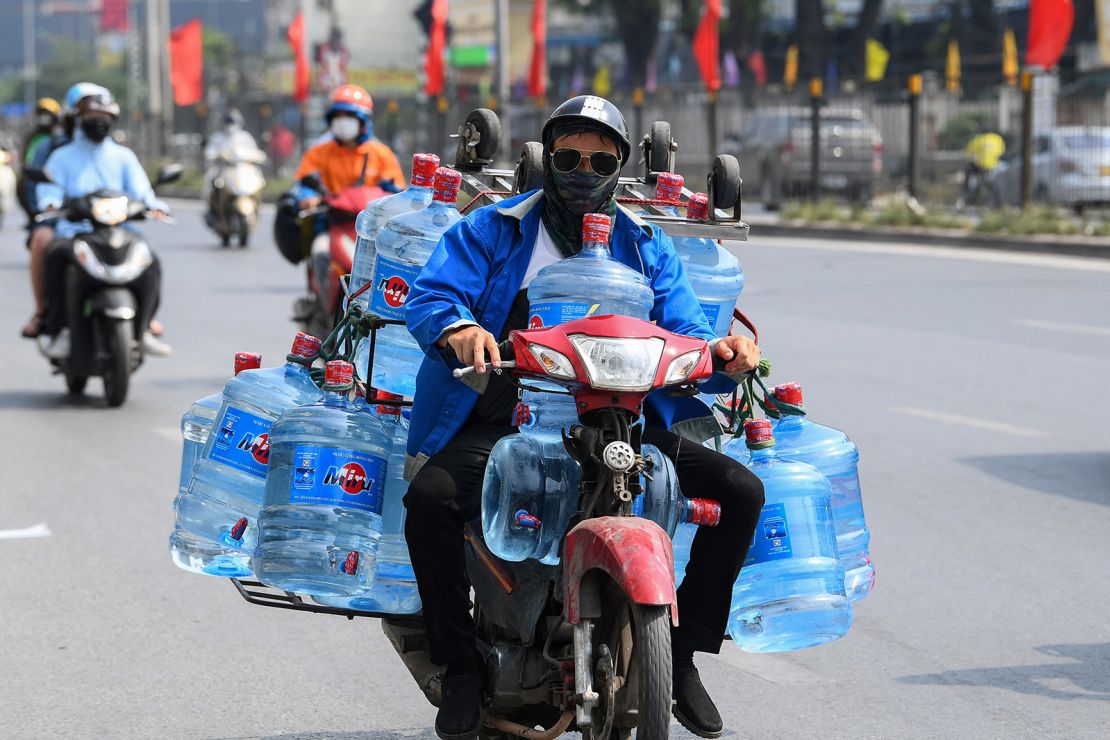 This photo taken on May 22, 2023, shows a man transporting containers of water on his motorbike in Hanoi, Vietnam.