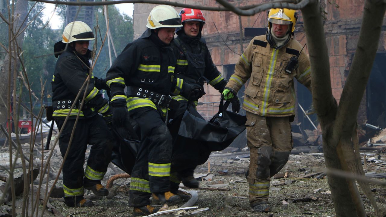 Los bomberos cargan un cuerpo después del mortal ataque ruso en Dnipro que mató al menos a dos personas.
