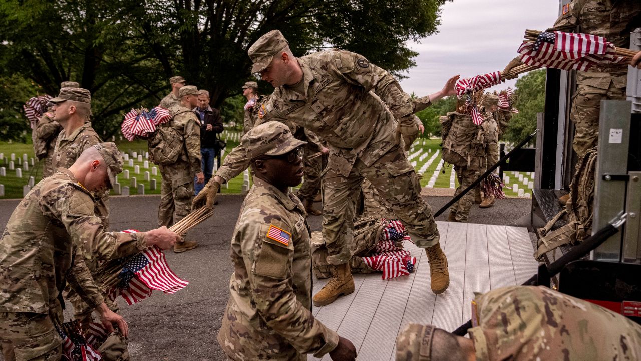 Members of the 3rd U.S. Infantry Regiment also known as The Old Guard, hand out flags to place them in front of each headstone for "Flags-In" at Arlington National Cemetery in Arlington, Thursday, May 25, 2023, to honor the Nation's fallen military heroes ahead of Memorial Day.