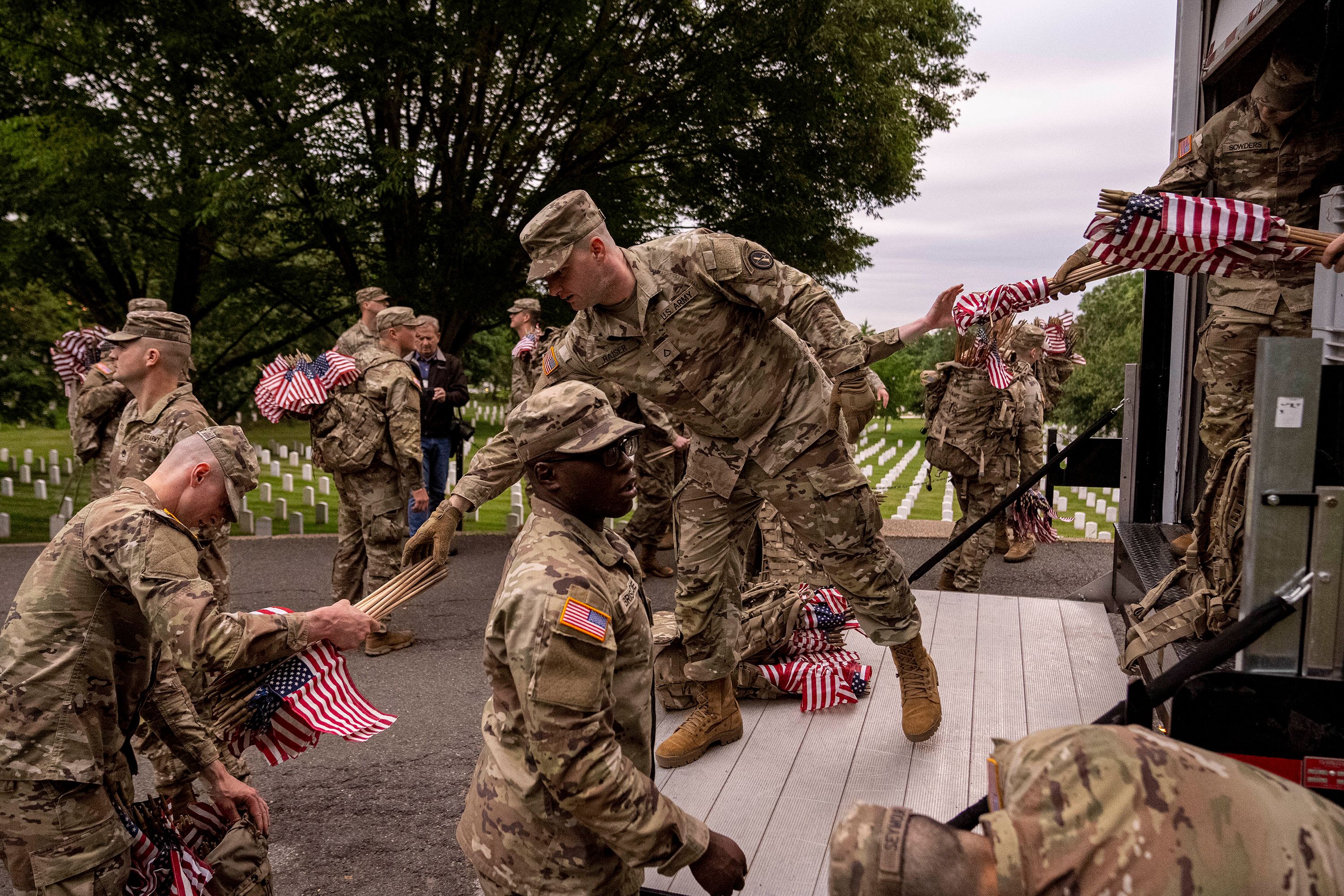 Members of the 3rd US Infantry Regiment hand out flags Thursday to be placed in Arlington National Cemetery.