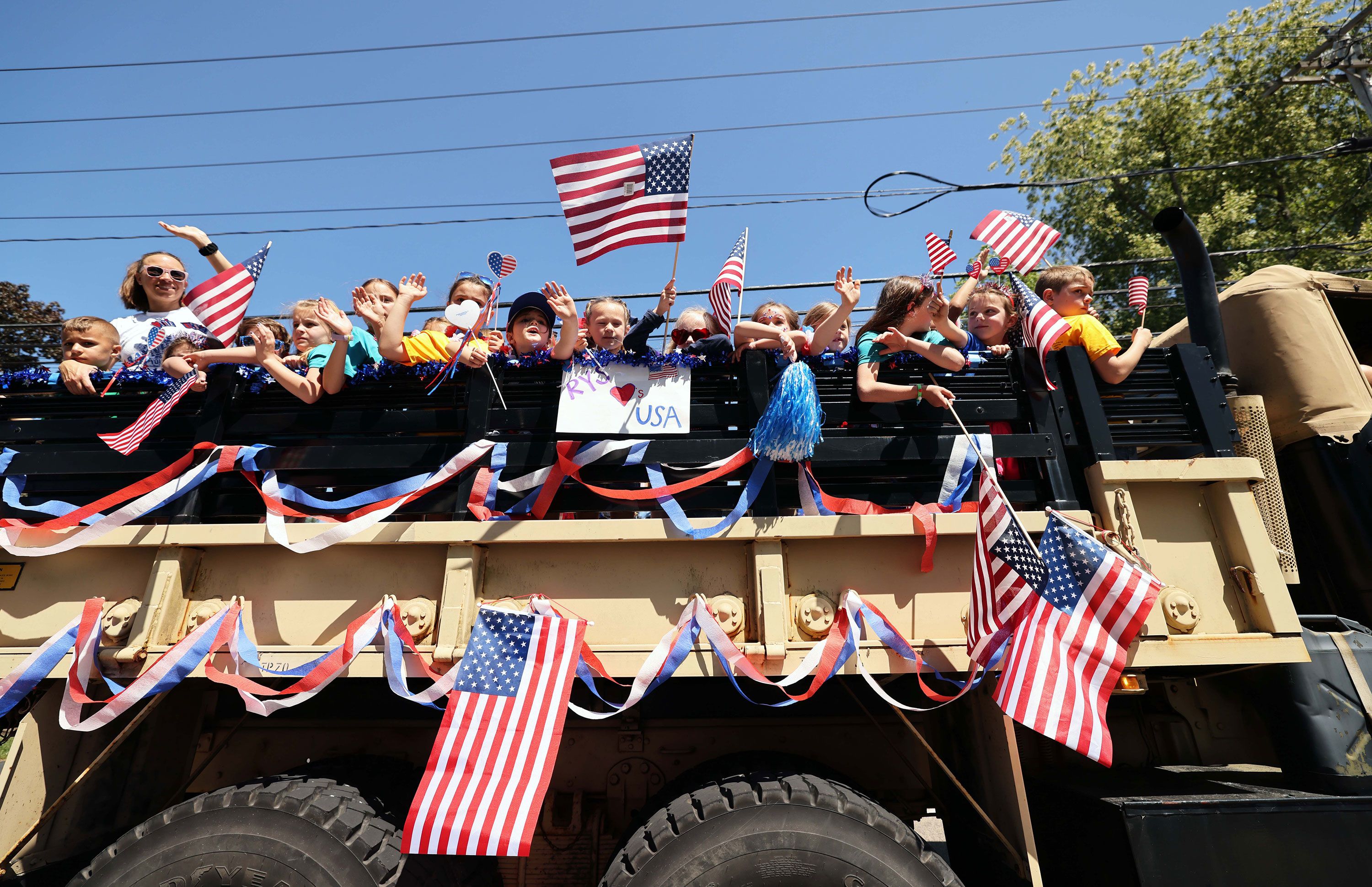 Students from Lillie B. Merrill Elementary School ride on a float during a Memorial Day Parade in Raynham, Massachusetts, on Saturday.