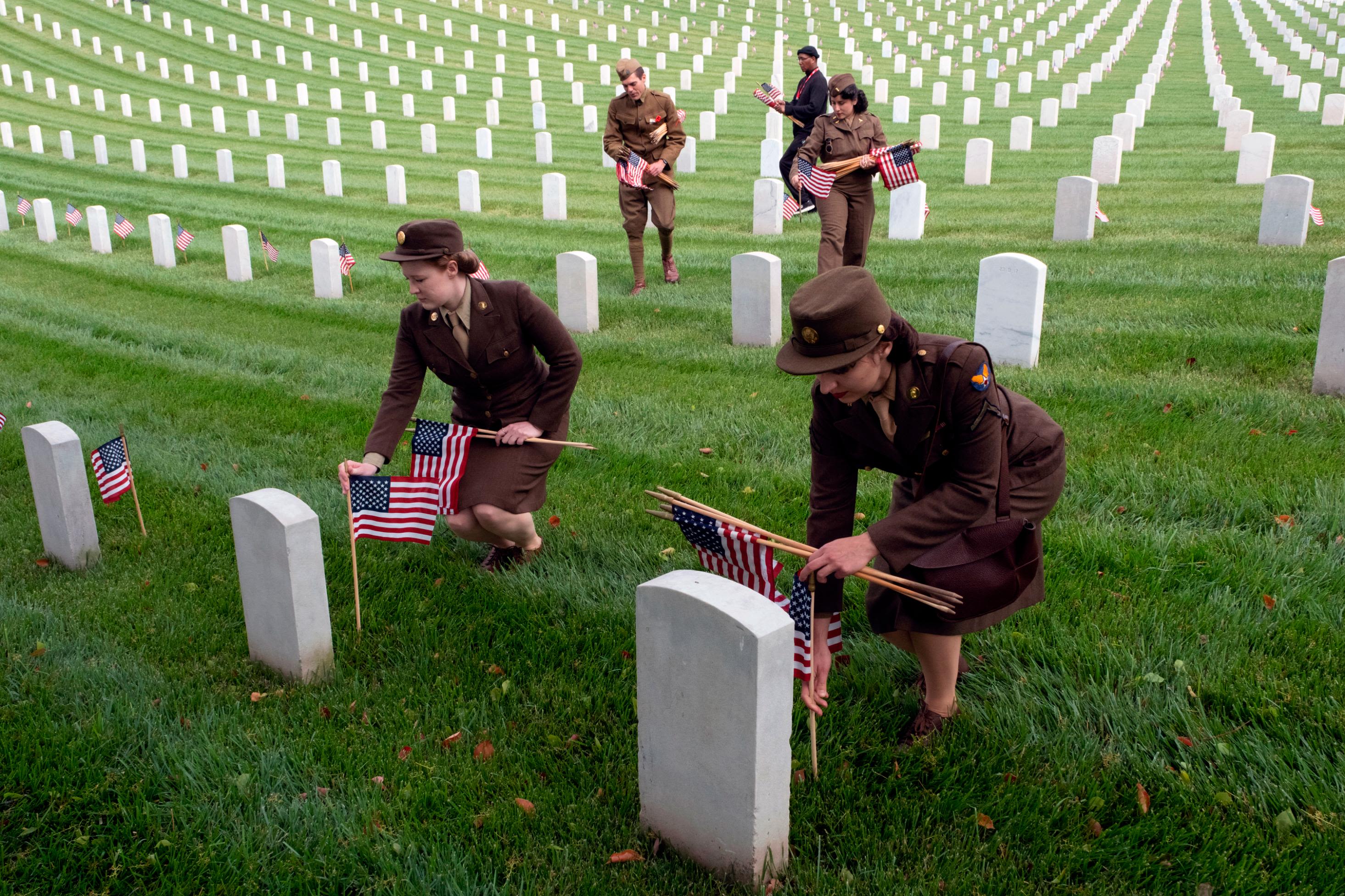 Shelby Anderson, left, and Carli Holland join members from the Historical Unit of Southern California and other volunteers to place flags at the Los Angeles National Cemetery on Saturday.