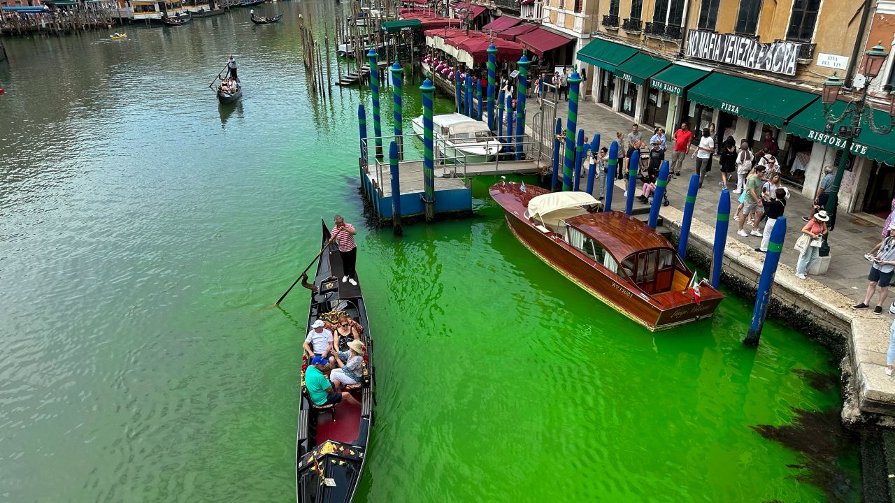 A gondola crosses Venice's historical Grand Canal as a patch of phosphorescent green liquid spreads in it, Sunday, May 28, 2023.