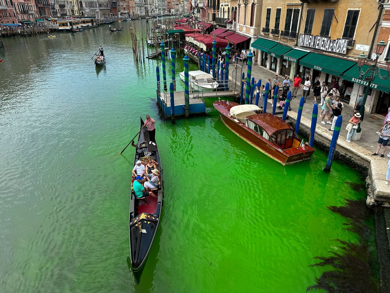 Một chiếc thuyền gondola băng qua Grand Canal lịch sử của Venice khi một mảng chất lỏng màu xanh lục phát quang lan rộng trong đó, Chủ nhật, ngày 28 tháng 5 năm 2023. Thống đốc vùng Veneto, Luca Zaia, cho biết các quan chức đã yêu cầu cảnh sát điều tra để xác định ai chịu trách nhiệm. khi các cơ quan môi trường cũng đang thử nghiệm nước.