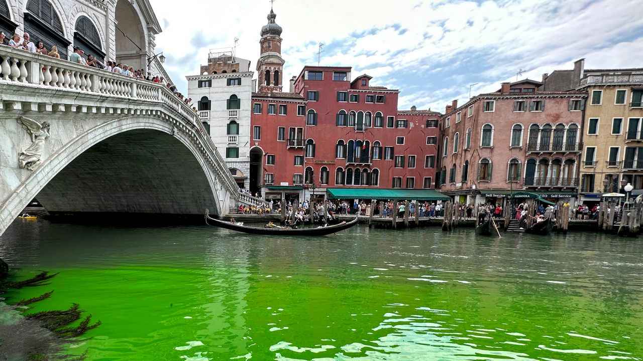 Gondolas navigate by the Rialto Bridge on Venice's historical Grand Canal as a patch of phosphorescent green liquid spreads in it, on Sunday, May 28, 2023. 
