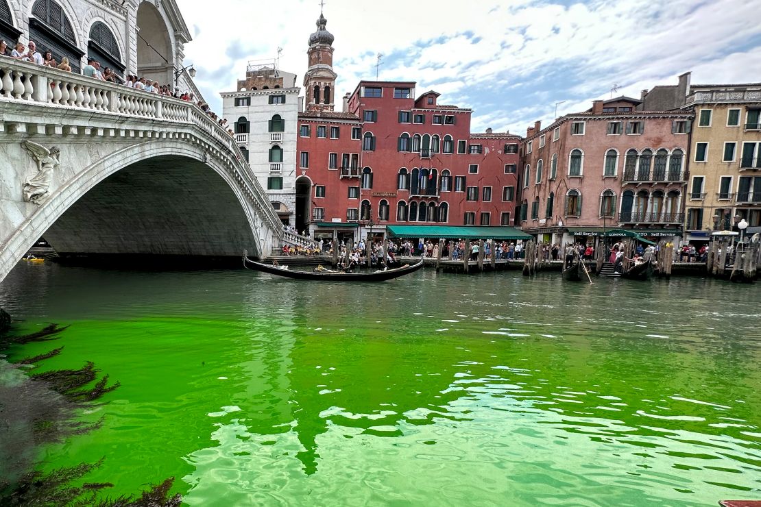 Gondolas navigate by the Rialto Bridge on Venice's historical Grand Canal as a patch of phosphorescent green liquid spreads in it, on Sunday, May 28, 2023. 