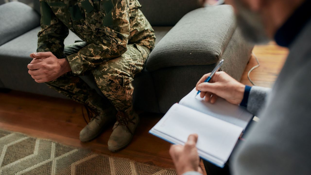 Cropped shot of military man during therapy session with psychologist. Soldier suffering from depression, psychological trauma. PTSD concept. Horizontal shot. Focus on military