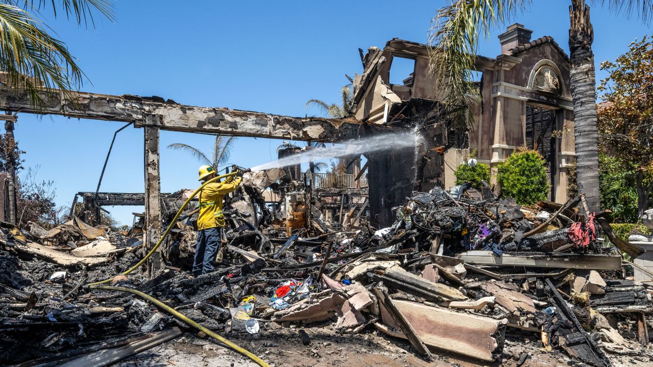 Laguna Niguel, CA - May 13: A firefighter puts out hot spots at a house on Coronado Pointe in Laguna Niguel, CA on Thursday, May 12, 2022. The Coastal fire destroyed 20 homes after starting on Wednesday, May 11, in Aliso Woods Canyon. (Photo by Paul Bersebach/MediaNews Group/Orange County Register via Getty Images)