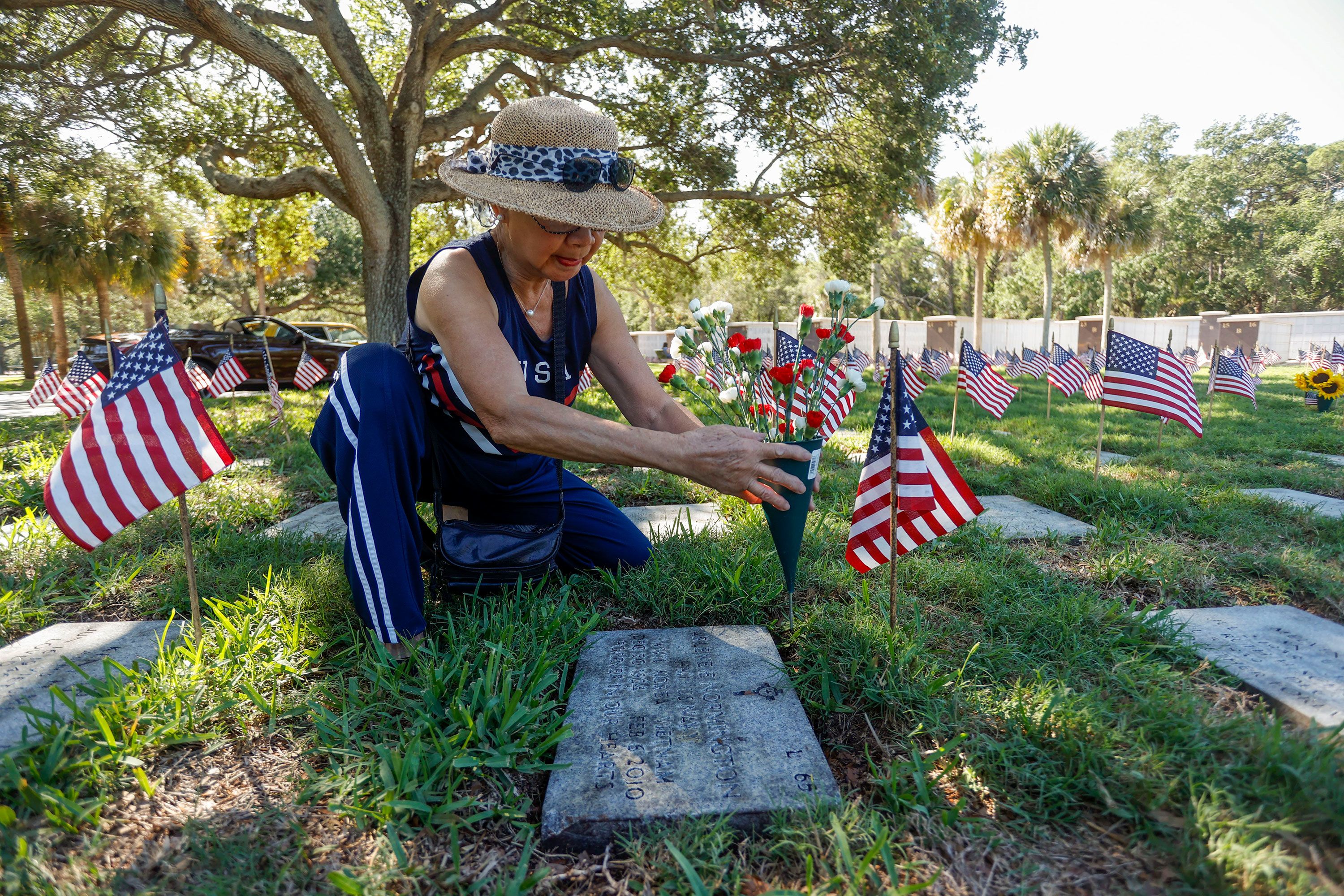 Cathy Normington sets fresh flowers on the gravesite of her husband's aunt Sunday at the Bay Pines National Cemetery in St. Petersburg, Florida.