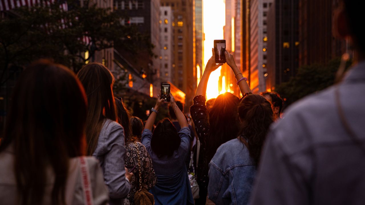 People photograph the Manhattanhenge sunset from East 42nd Street, on Monday, July 11, 2022, in New York.