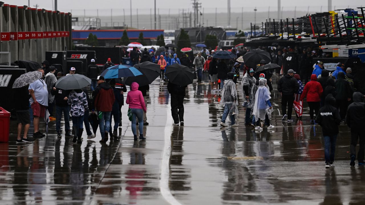 Race fans walk through the garage area while rain causes a delay to a NASCAR Cup Series race at Charlotte Motor Speedway on Sunday.
