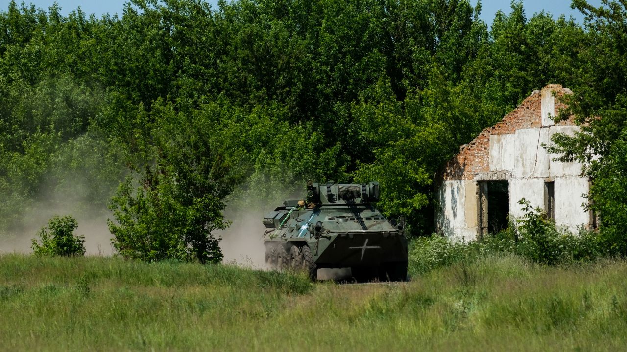 Un vehículo blindado de transporte de personal BTR ucraniano acelera a través de un campo como parte de un ejercicio militar.