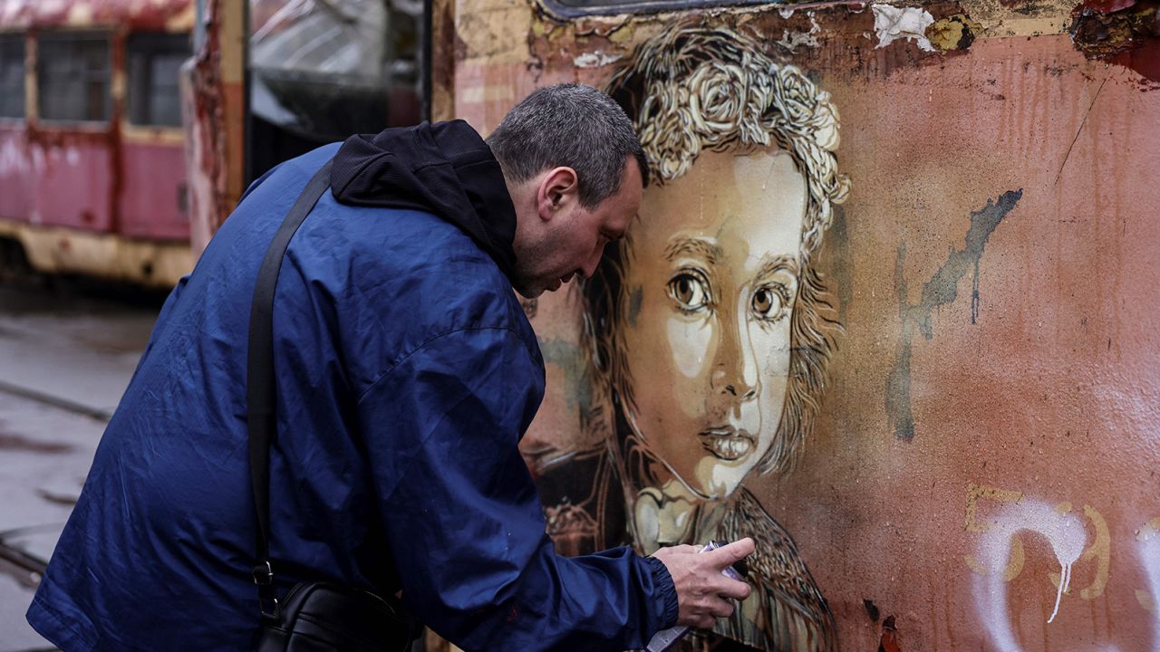 TOPSHOT - French street-artist  Christian Guemy, known as C215, paints one of his works next to a metro station and food market that were badly damaged by a Russian strike in Kyiv on April 1, 2022. (Photo by RONALDO SCHEMIDT / AFP) (Photo by RONALDO SCHEMIDT/AFP via Getty Images)