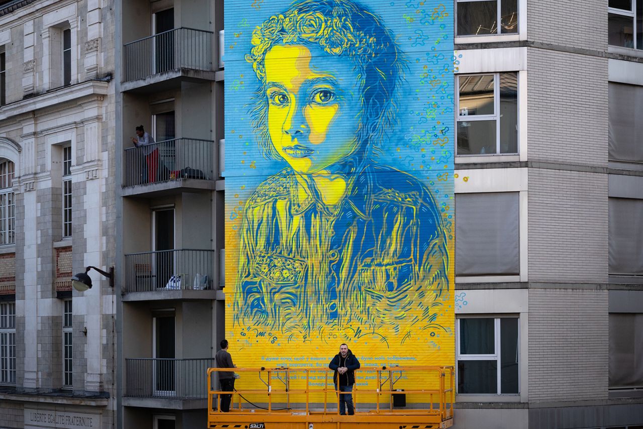 French street artist and painter Christian Guemy (R) known as C215 poses in front of his fresco depicting a Ukrainian young girl with a quote attributed to Ukrainian President Volodymir Zelensky I really don't want my photos in your offices, because I am neither a god nor an icon, but rather a servant of the Nation. Instead, hang pictures of your children and look at them whenever you want to make a decision. » in Paris on March 10, 2022, - - RESTRICTED TO EDITORIAL USE - MANDATORY MENTION OF THE ARTIST UPON PUBLICATION - TO ILLUSTRATE THE EVENT AS SPECIFIED IN THE CAPTION (Photo by JOEL SAGET / AFP) / RESTRICTED TO EDITORIAL USE - MANDATORY MENTION OF THE ARTIST UPON PUBLICATION - TO ILLUSTRATE THE EVENT AS SPECIFIED IN THE CAPTION / RESTRICTED TO EDITORIAL USE - MANDATORY MENTION OF THE ARTIST UPON PUBLICATION - TO ILLUSTRATE THE EVENT AS SPECIFIED IN THE CAPTION (Photo by JOEL SAGET/AFP via Getty Images)