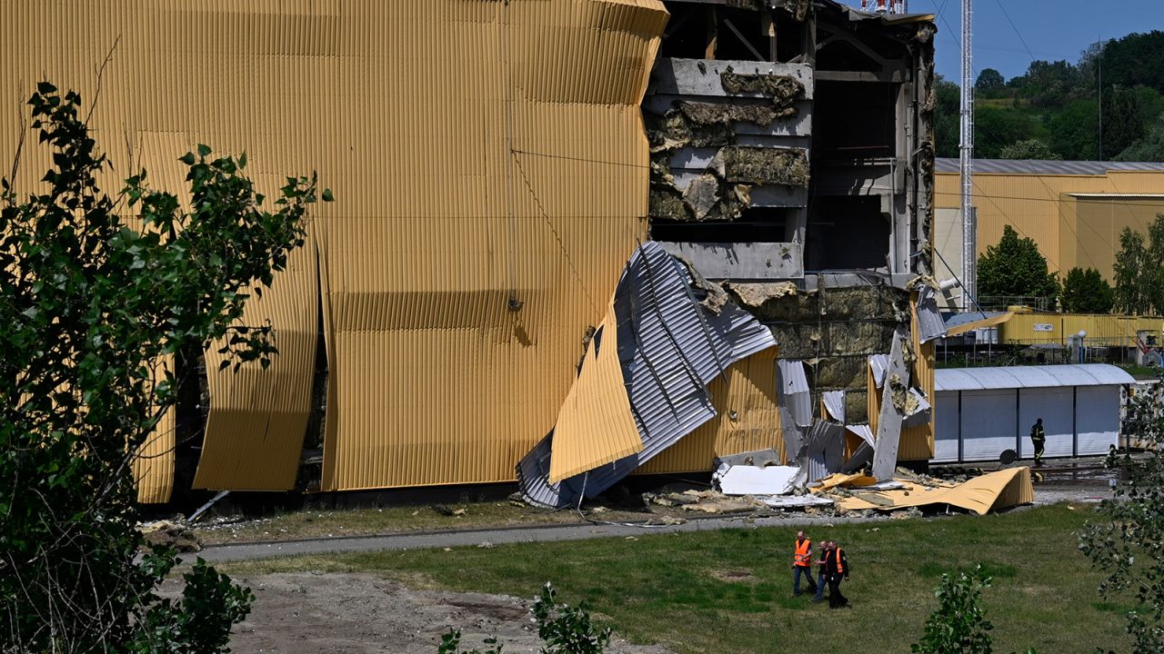 People walk near the damaged industrial building that was damaged in an attack by the Iranian Shahed attack drone of the Russian army in Kyiv on May 28, 2023.