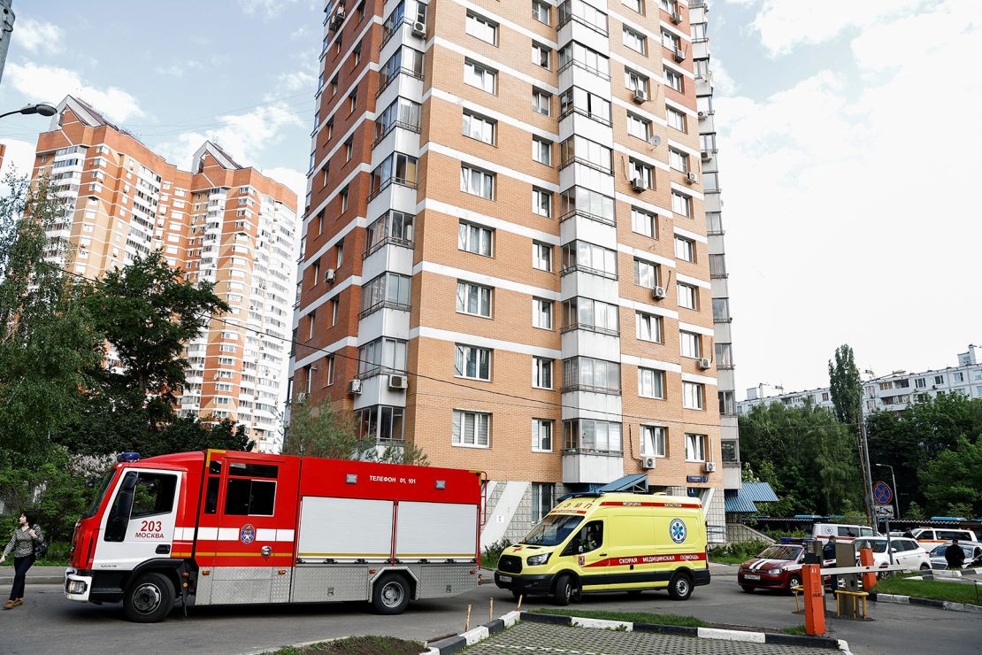 An ambulance and firefighting vehicles are parked outside a multi-storey apartment block following a reported drone attack in Moscow, Russia.