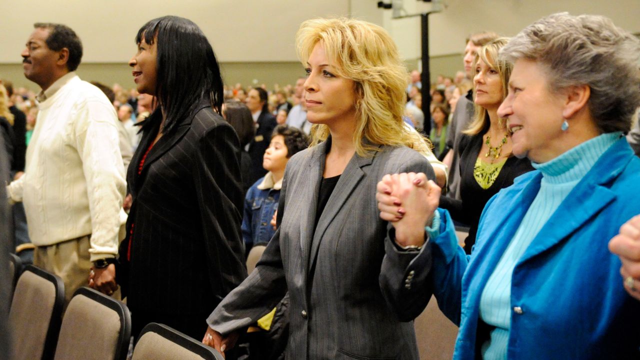 Jeanne Assam, second right, the security guard who shot and wounded an armed assailant in the New Life Church after services on Sunday, holds hands with worshippers during the family service at the church in Colorado Springs, Colo., on Wednesday, Dec. 12, 2007. A lone gunman killed two worshippers outside the church after services on Sunday and was gunned down by a security guard when he entered the building. The gunman is also connected to a double shooting at a missionary school in the northwest Denver suburb of Arvada, Colo., roughly 12 hours before the massacre at the New Life Church.  (AP Photo/Jerilee Bennett, Pool)