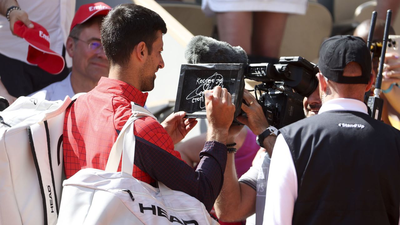 Djokovic writes a message on a TV camera lens at Roland-Garros. 