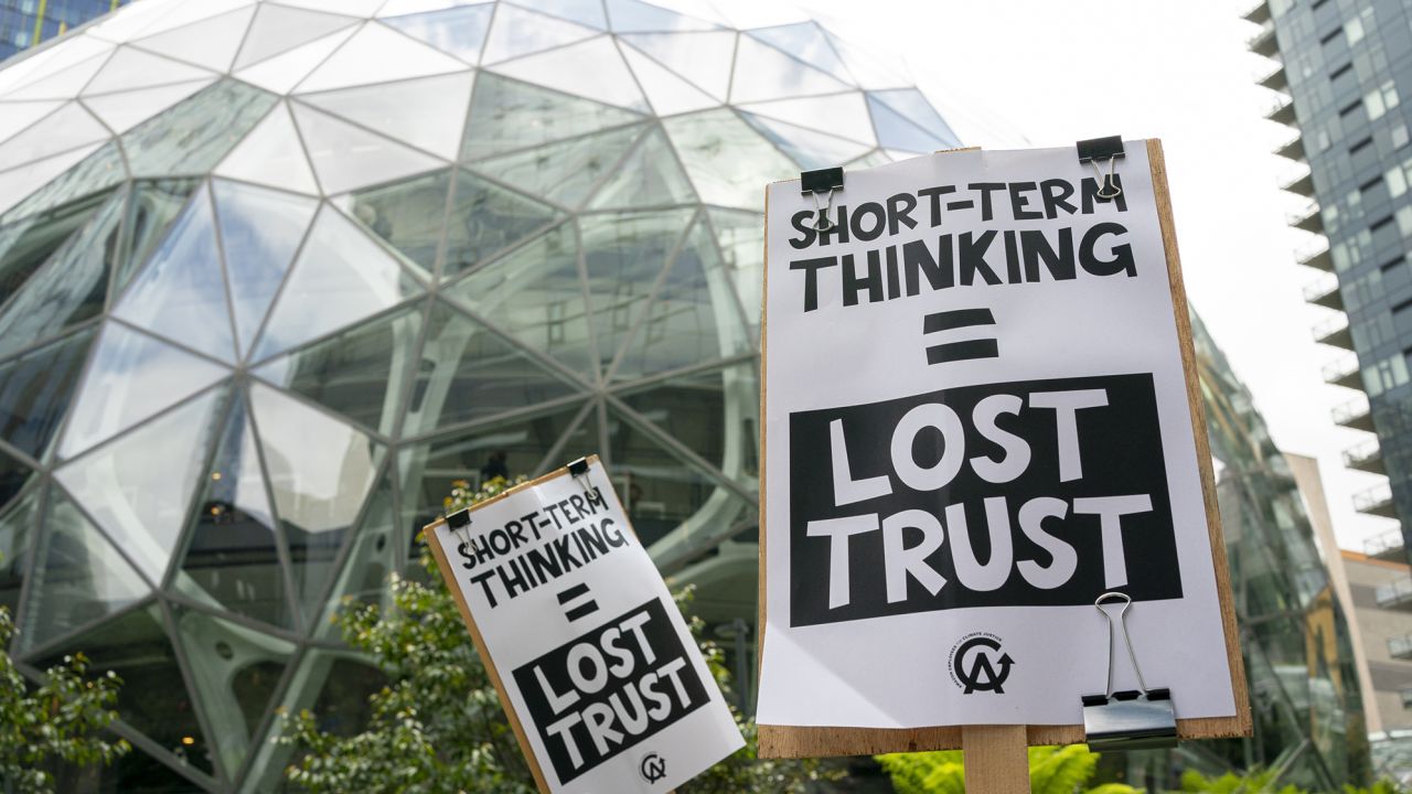 Amazon workers hold signs during a walkout event at the company's headquarters on May 31, 2023 in Seattle, Washington. The protest action was organized to call attention to return to office requirements, in addition to recent layoffs and climate change issues. 