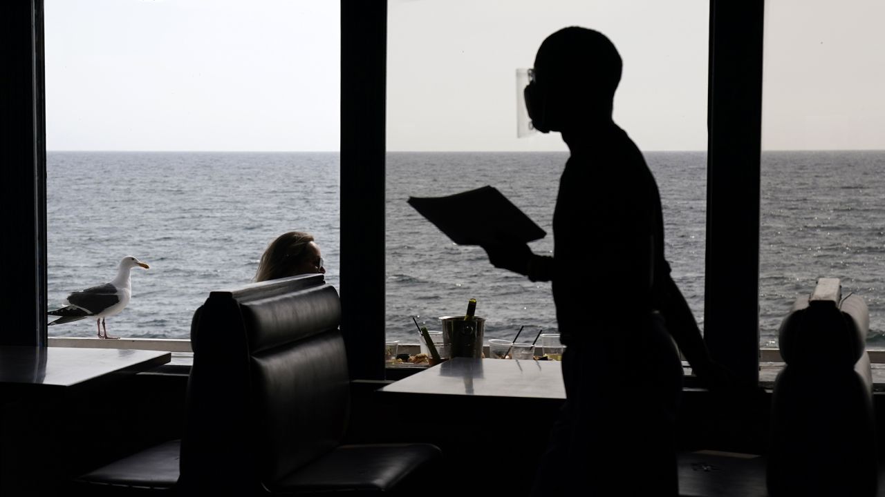 A waiter walks through an empty dining room as diners eat outside in front of beach views at Gladstone's restaurant Sunday, March 14, 2021, in the Pacific Palisades section of Los Angeles.