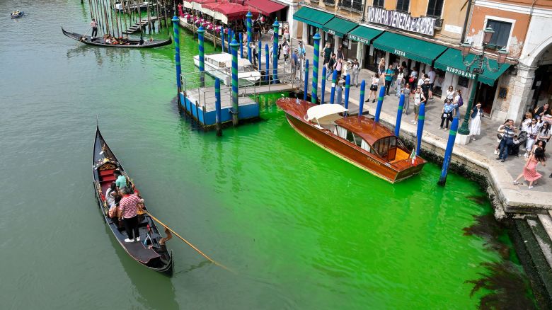 A gondola navigates along Venice's historical Grand Canal as a patch of phosphorescent green liquid spreads in it, Sunday, May 28, 2023. The governor of the Veneto region, Luca Zaia, said that officials had requested the police to investigate to determine who was responsible, as environmental authorities were also testing the water. (AP Photo/Luigi Costantini)