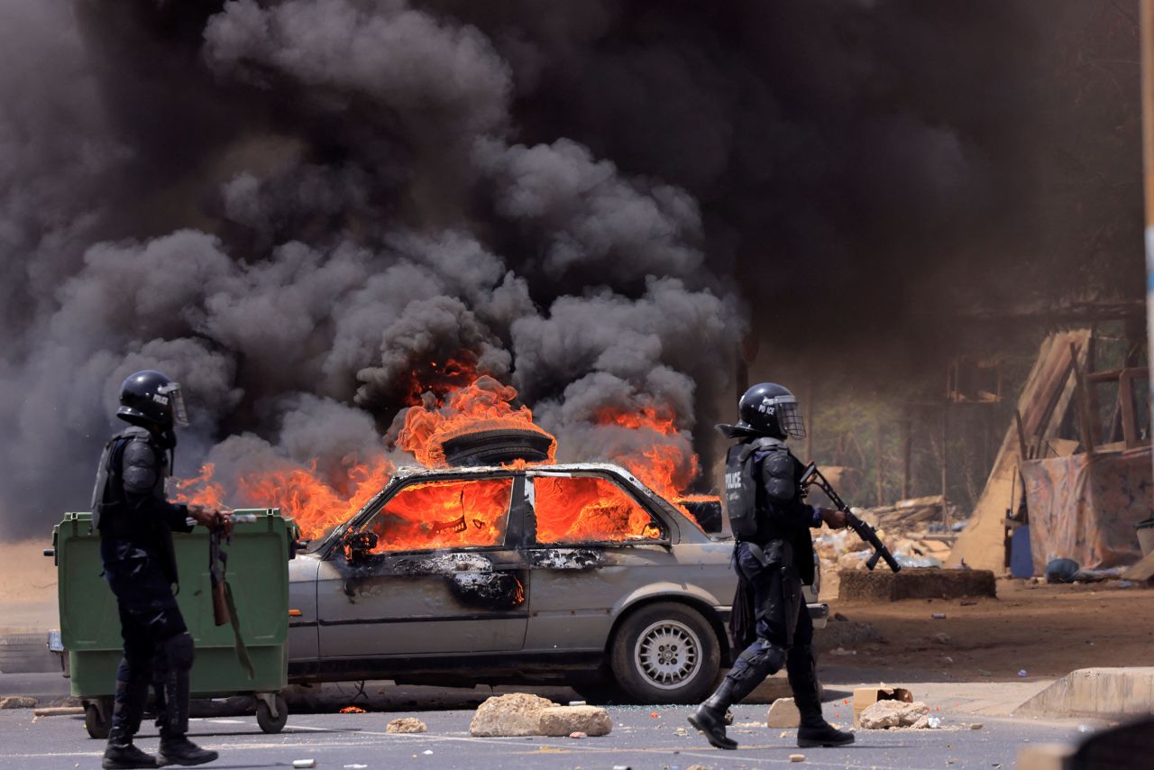 Police officers in Dakar, Senegal, walk near a car that was set on fire during clashes between security forces and supporters of opposition leader Ousmane Sonko on Thursday, June 1. Sonko was sentenced to two years in prison for "corrupting youth," according to state media, and <a href="https://www.cnn.com/2023/06/01/africa/senegalese-opposition-leader-jailed-intl/index.html" target="_blank">his conviction</a> means he will not be eligible to stand for the country's 2024 elections.
