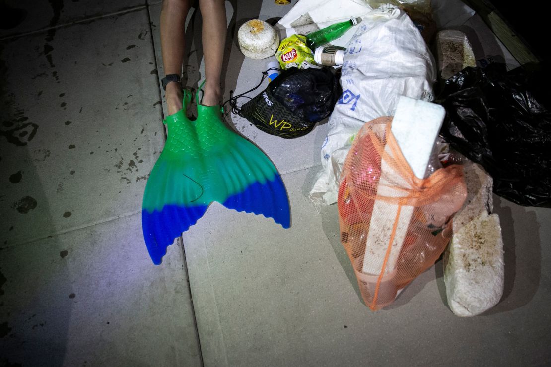 Merle Liivand sits next to a pile of trash that she picked while swimming 30 miles around Biscayne Bay wearing a mermaid tail, to create awareness on plastic pollution and climate change, in Miami Beach, Florida, U.S. April 15, 2023.