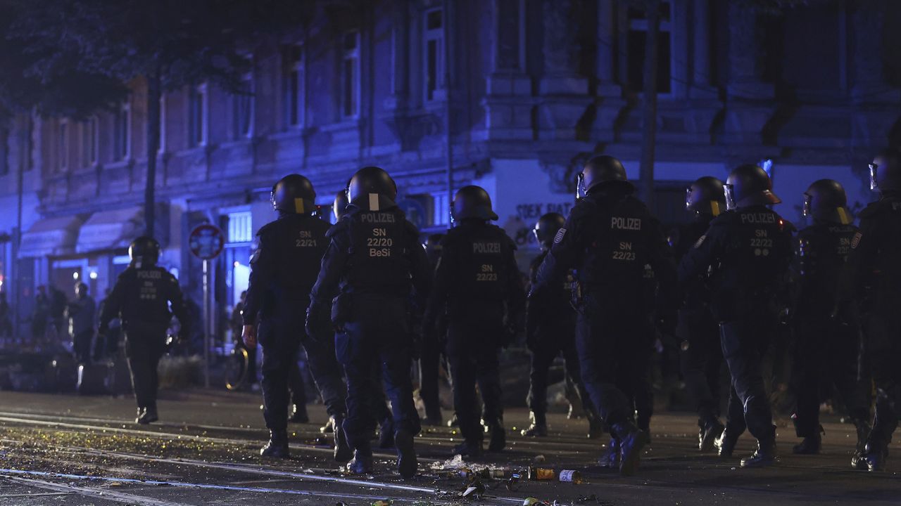 Police officers walk across a street strewn with broken glass after left-wing protests against the verdict in the trial of Lina E. on May 31 in Leipzig.