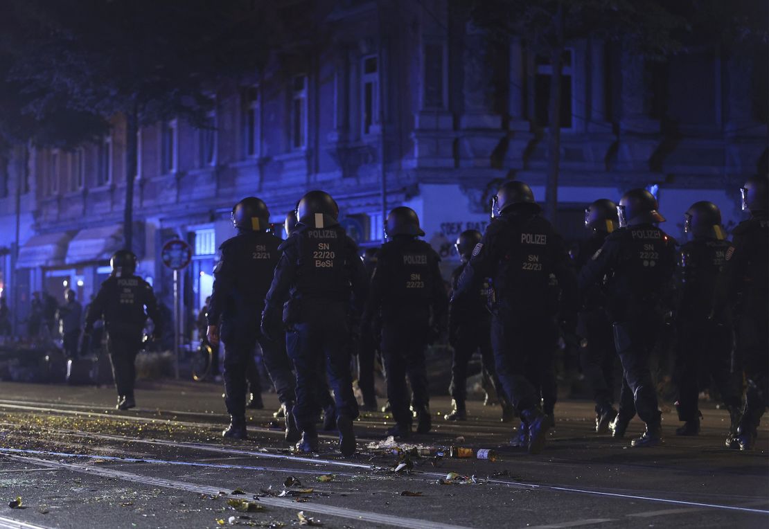 Police officers walk across a street strewn with broken glass after left-wing protests against the verdict in the trial of Lina E. on May 31 in Leipzig.